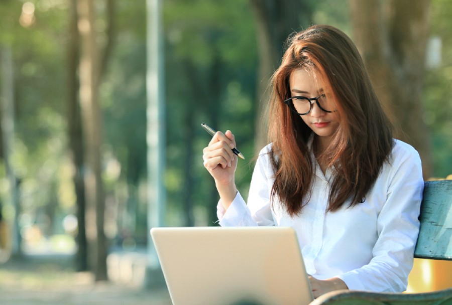 Woman with glasses using her laptop outside